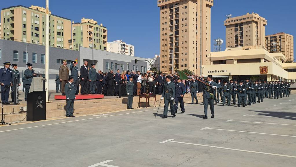 Formación y desfile de guardias civiles en el patio de la Comandancia de Las Palmas, con autoridades en la tribuna y edificios residenciales al fondo bajo un cielo despejado.